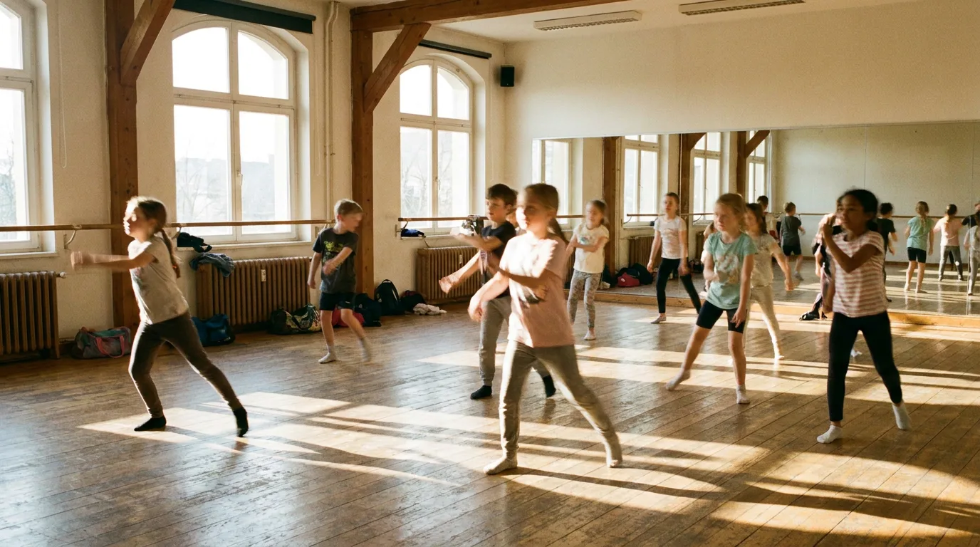 Children practising movement in a sunlit dance studio with mirrors and wooden floors.